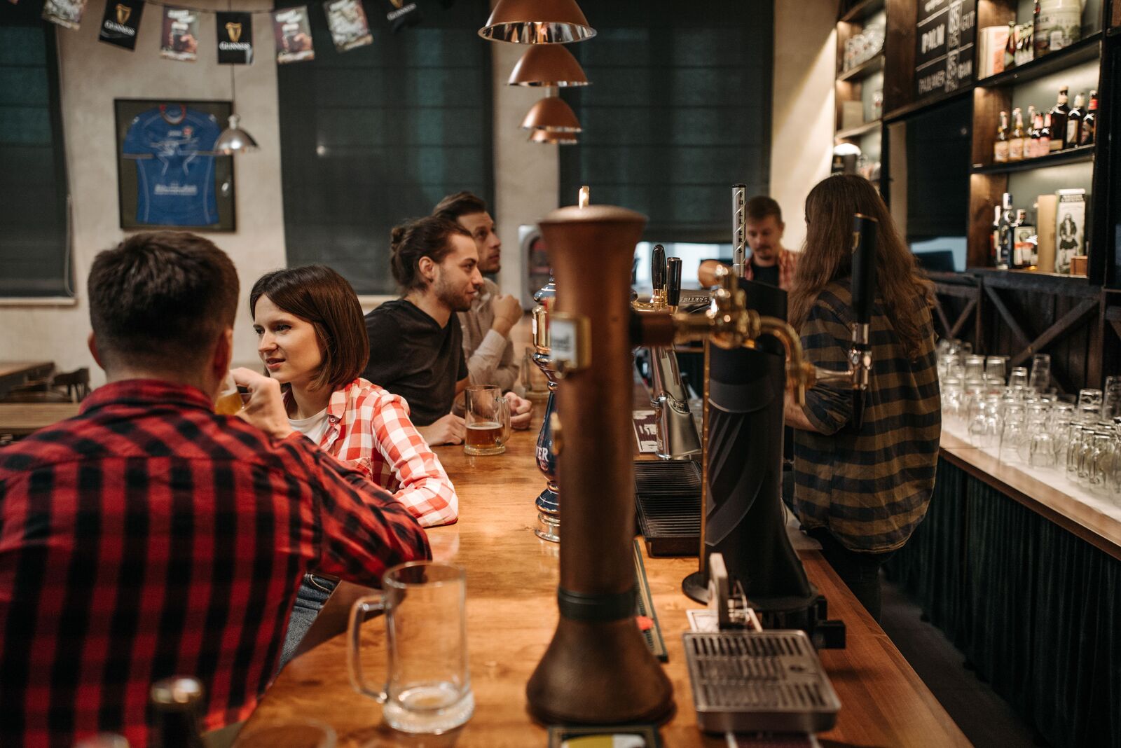 A warm bar at night, pairs of people deep in conversation along the counter