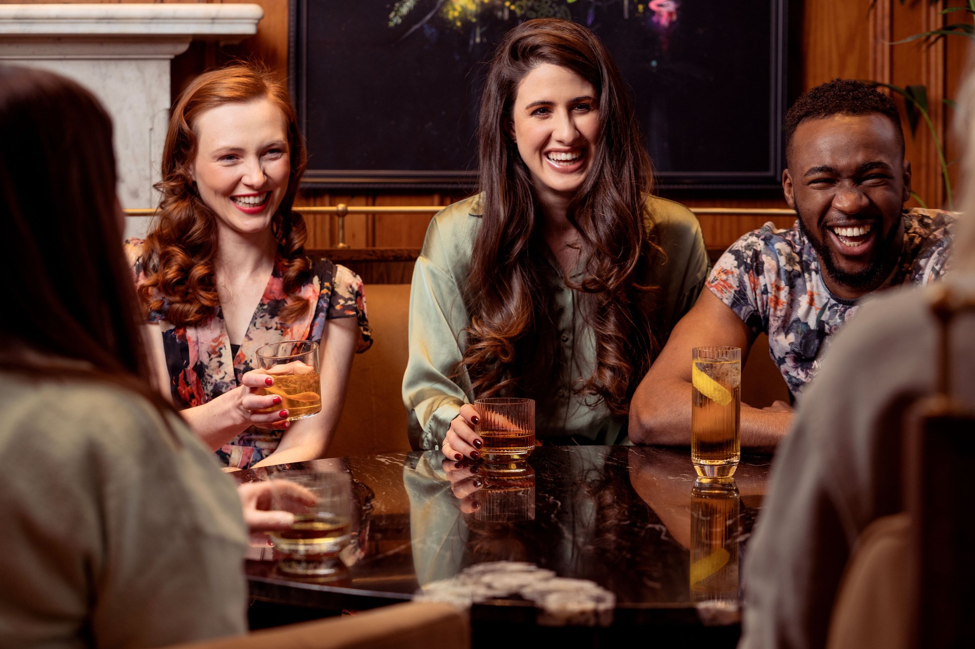 A group of friends laughing together over drinks in a warm bar